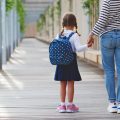 A mother holding a child with a back pack - How To Enjoy Summer And Back To School Prep Tips
