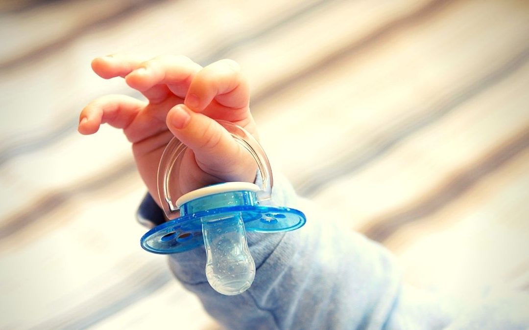 a baby hand holding a pacifier