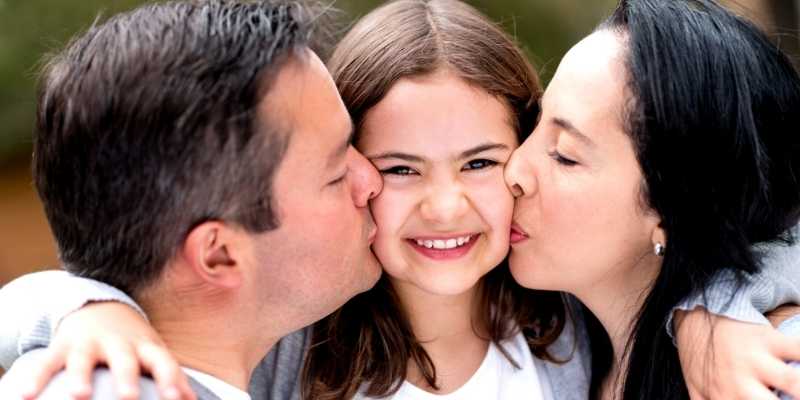mom and dad kissing loving daughter