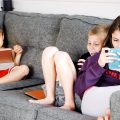 three kids sitting on the sofa browsing mobile phones-parental mobile phone tracker app
