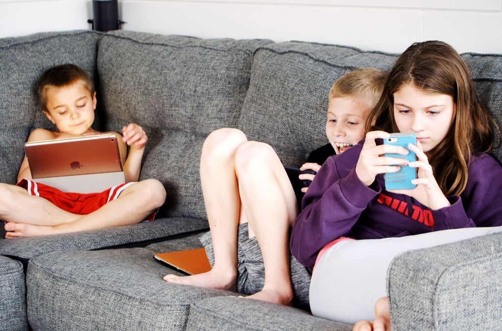 three kids sitting on the sofa browsing mobile phones-parental mobile phone tracker app