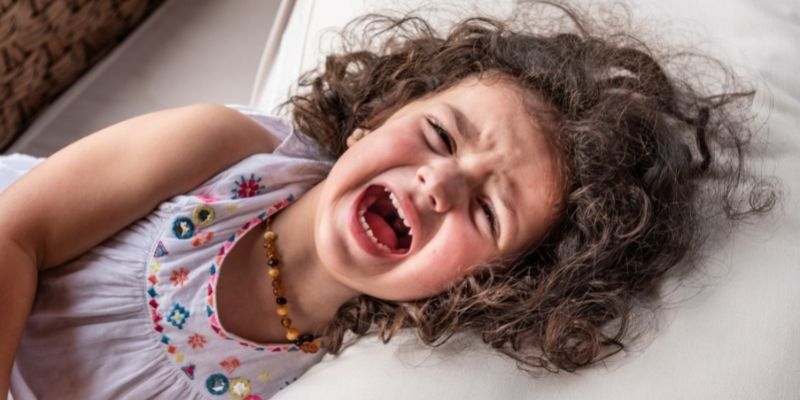 a child tantrum and crying on the bed