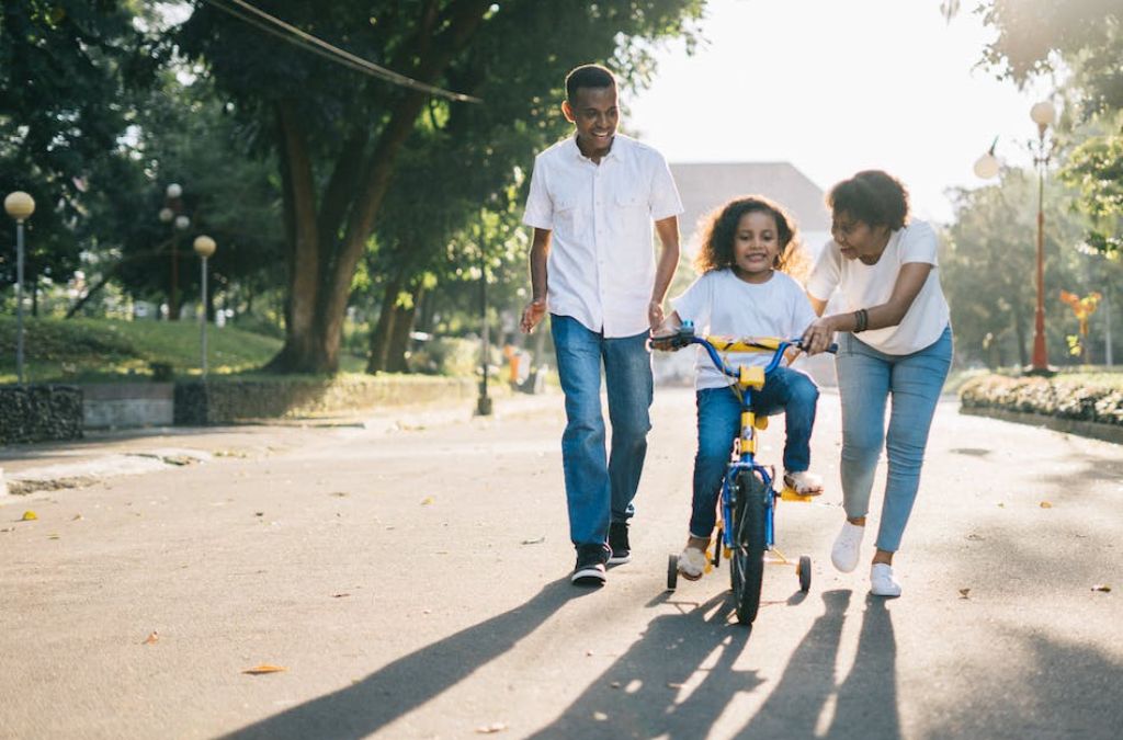 A mother and father teaching child to bike spending quality family time in a park