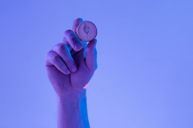 Male hand with golden Ethereum on blue background